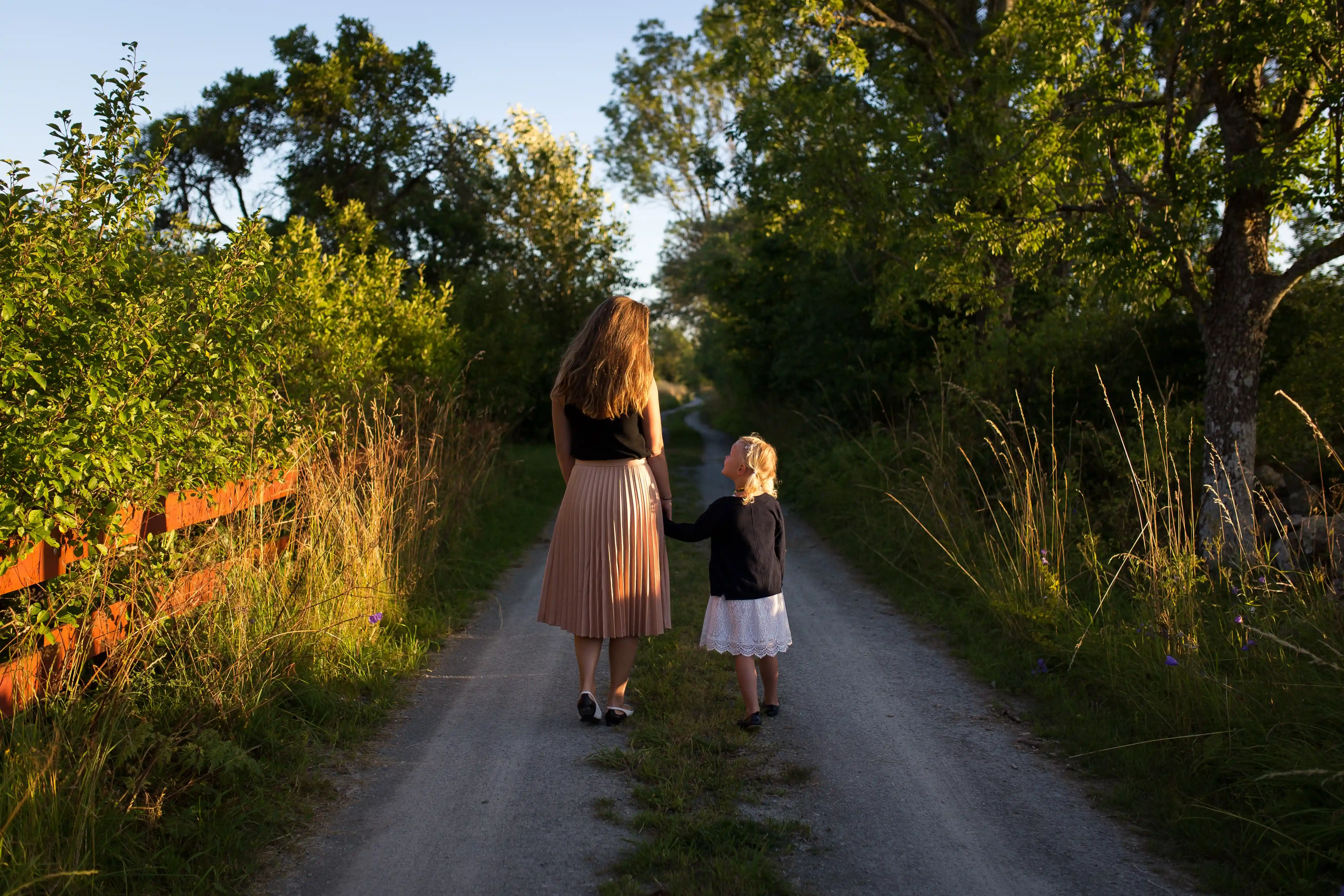 Mor og datter går hånd i hånd i en skov